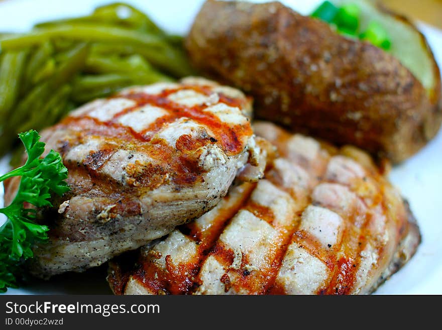 Delicious pork chop meal with a baked potato. Delicious pork chop meal with a baked potato