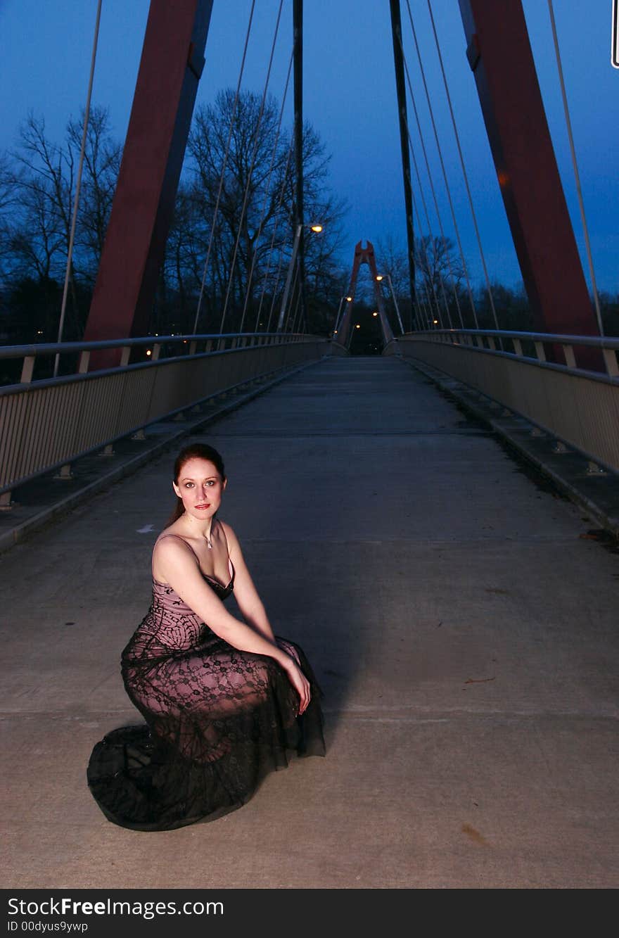 Tall female fashion model poses on a walkway at twilight. Tall female fashion model poses on a walkway at twilight.