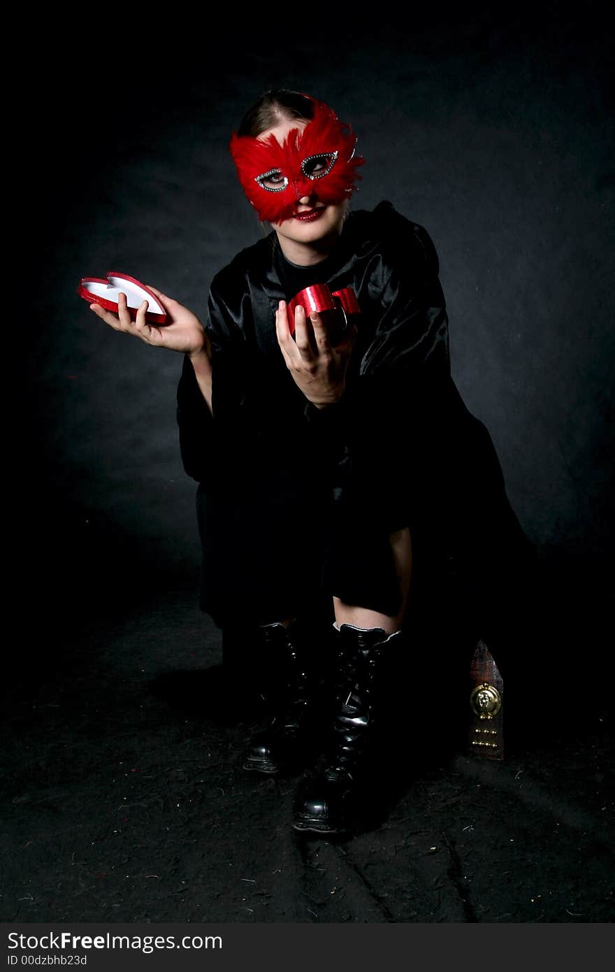 Women in red mask with open box in hands. Make-up black background. Women in red mask with open box in hands. Make-up black background.