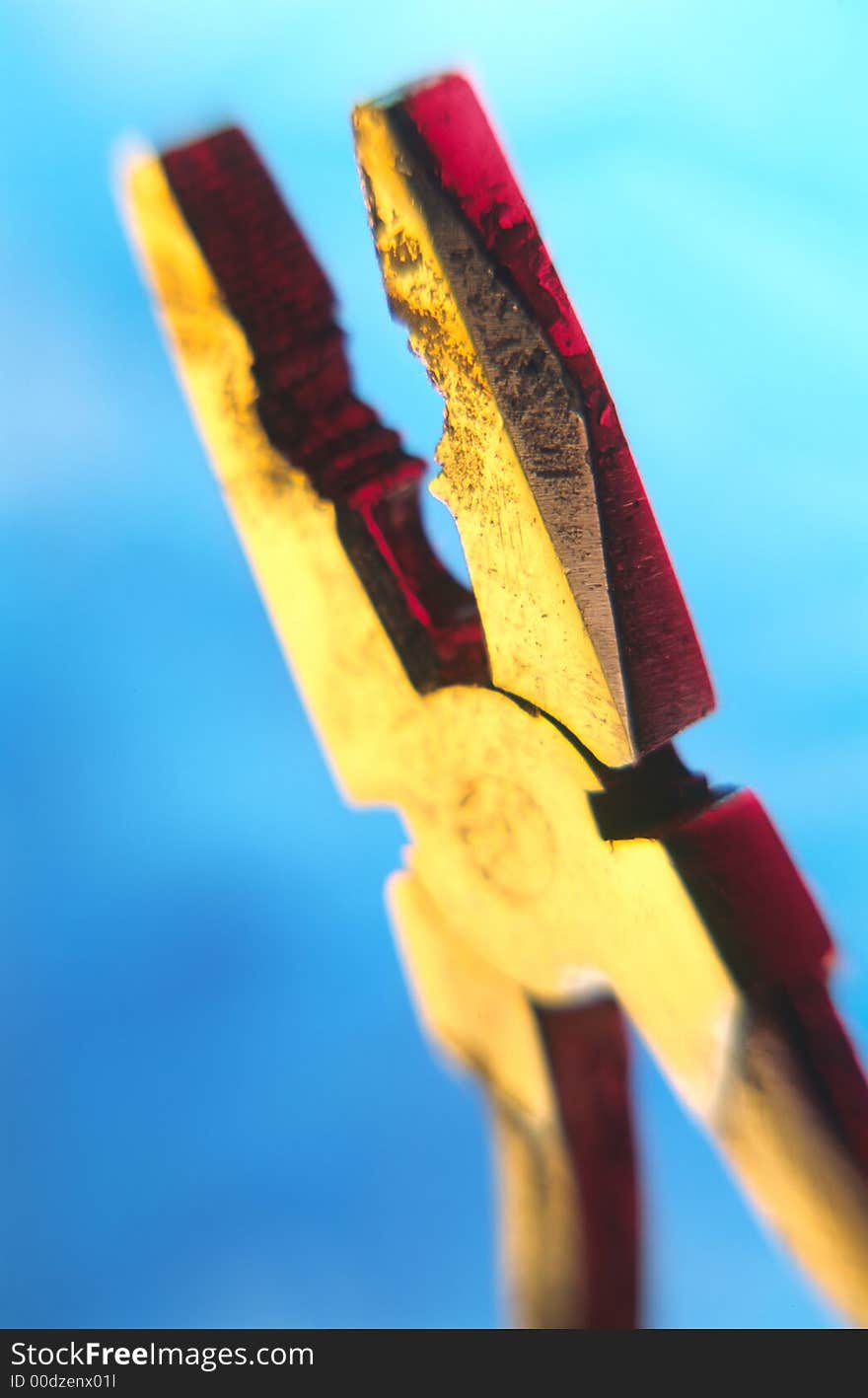 Old flat-nose pliers covered by light on  blue background,  close up