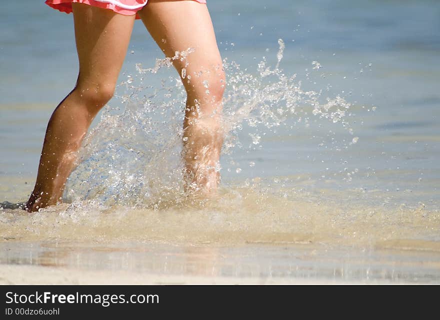 Girl wading and splashing along the beach. Girl wading and splashing along the beach