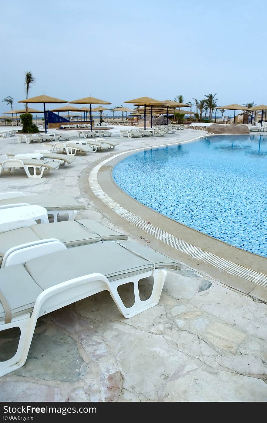 View at the resort pool with chairs and shades early in the morning. View at the resort pool with chairs and shades early in the morning