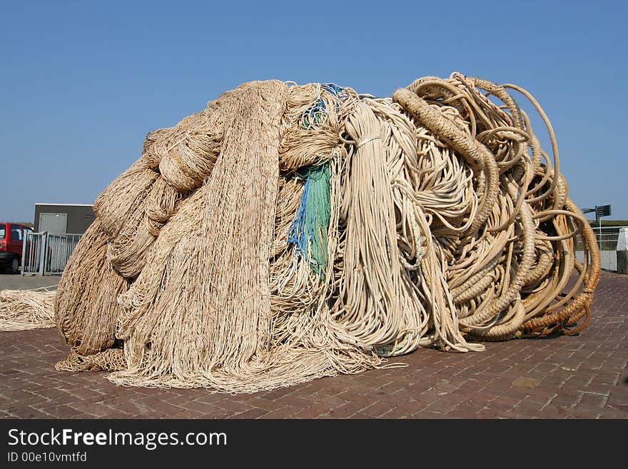 Pile of ropes and fishing nets on the quay of a fishing port