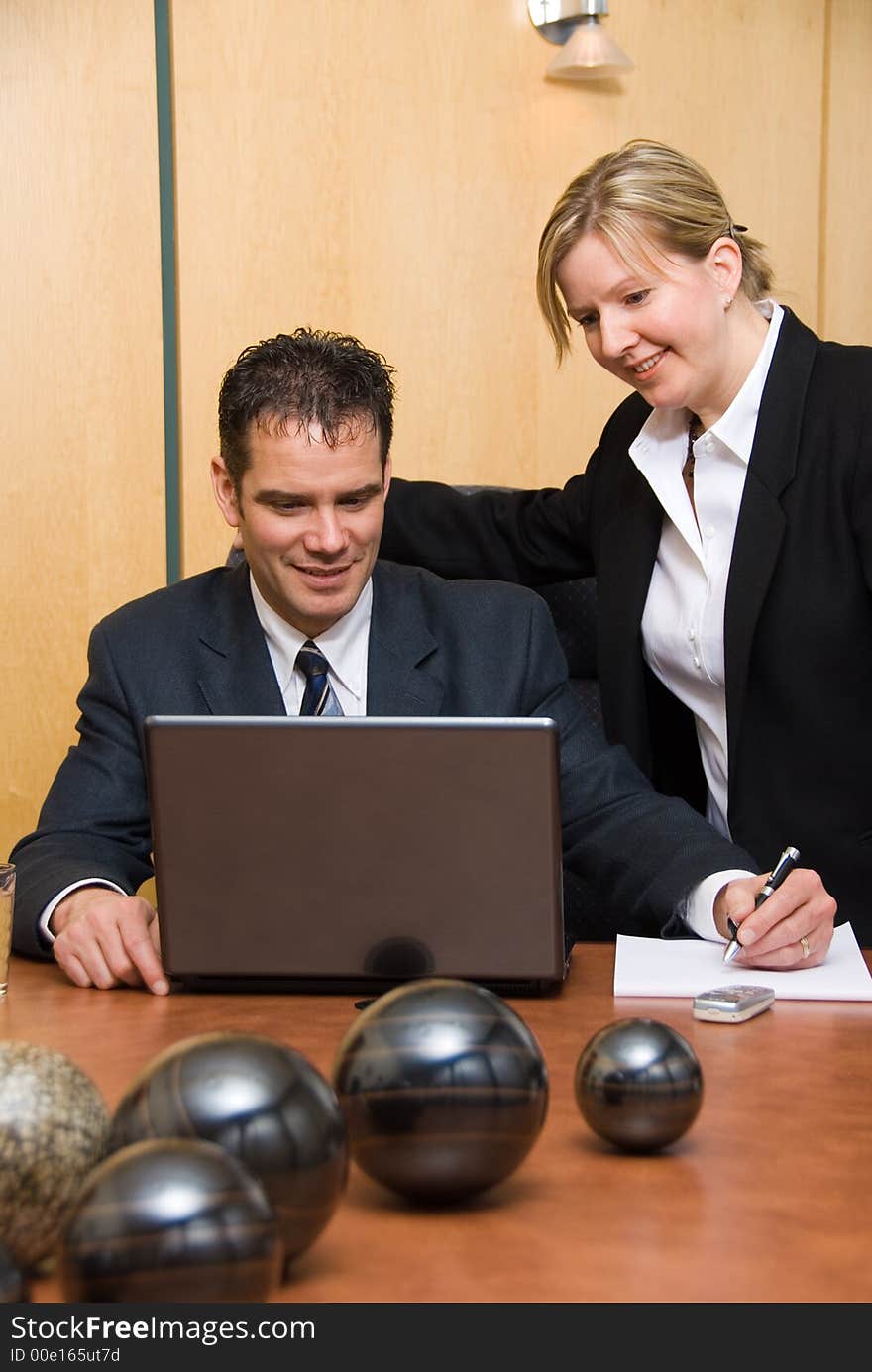 Man and woman in a room with a laptop writing on paper. Man and woman in a room with a laptop writing on paper