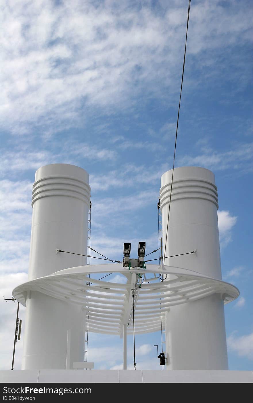 A pair of white ships smokestacks against clouds and sky