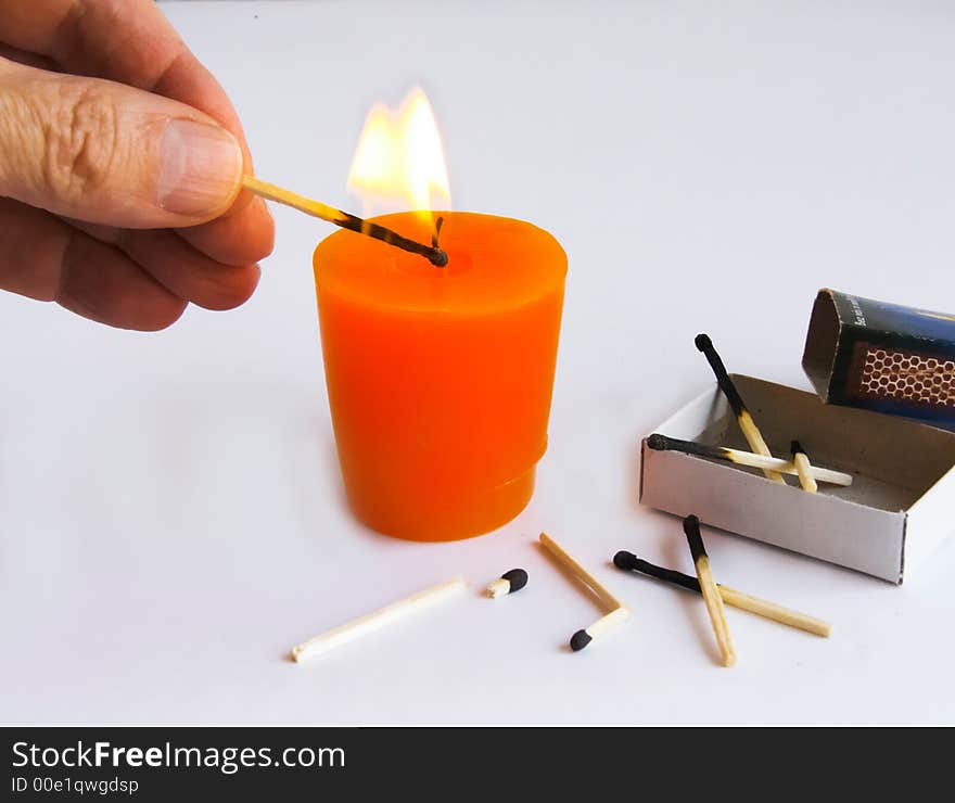 Burning candle, matchbox and hand holding a  ignition of match - on white background. Burning candle, matchbox and hand holding a  ignition of match - on white background