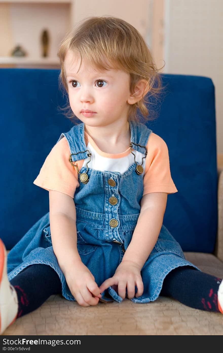 Little cute girl sitting on the sofa.