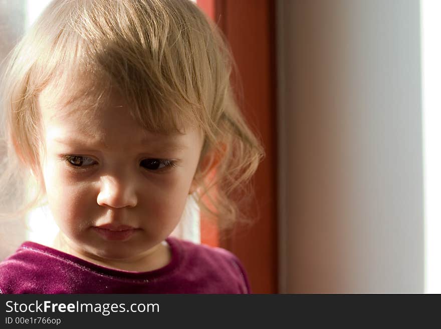 Cute little offended girl alight with rays of sun