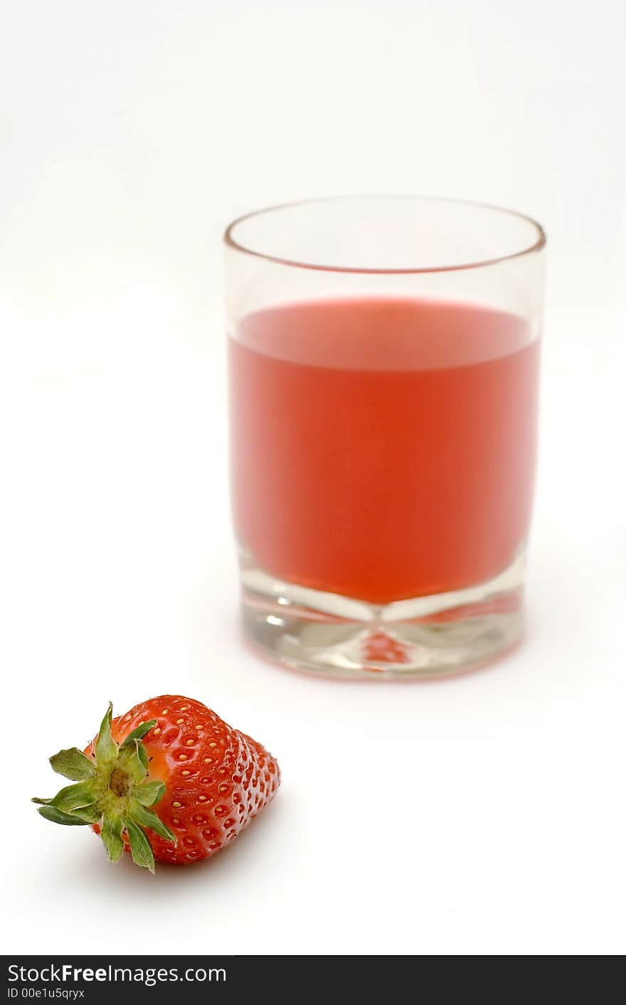 A fresh strawberry and a glass of strawberry juice. A fresh strawberry and a glass of strawberry juice