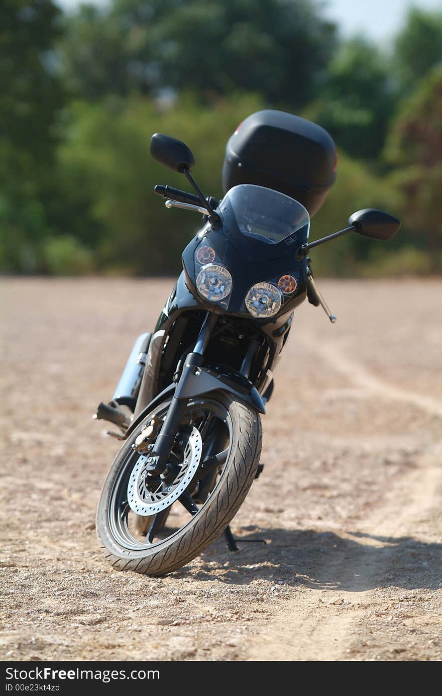 Front of black sports motorbike parked on sand. Shallow depth of field. Front of black sports motorbike parked on sand. Shallow depth of field.