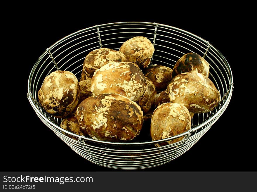 Wire bowl full of baked potatoes on a black background. Wire bowl full of baked potatoes on a black background