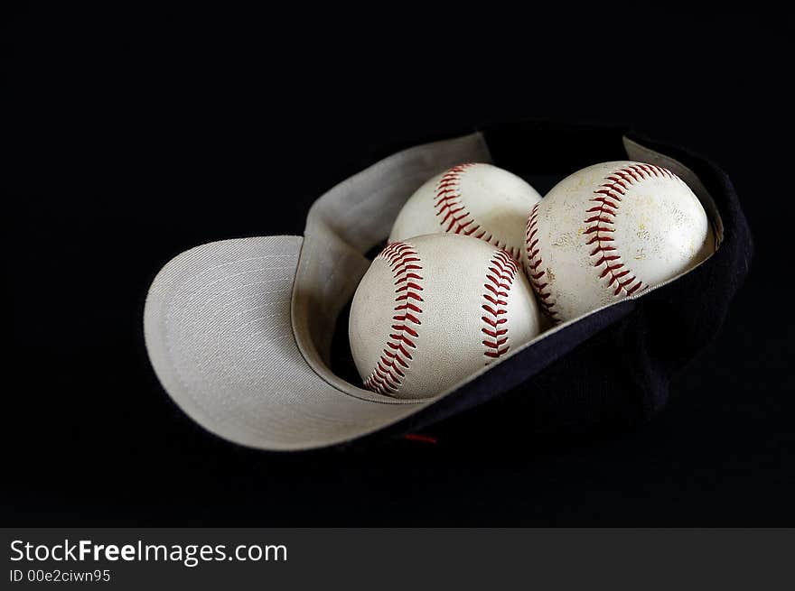 Blue baseball hat and three balls inside on a black background