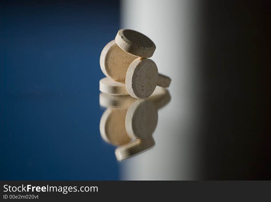 A pile of pills with reflection and blue,white and black background. A pile of pills with reflection and blue,white and black background