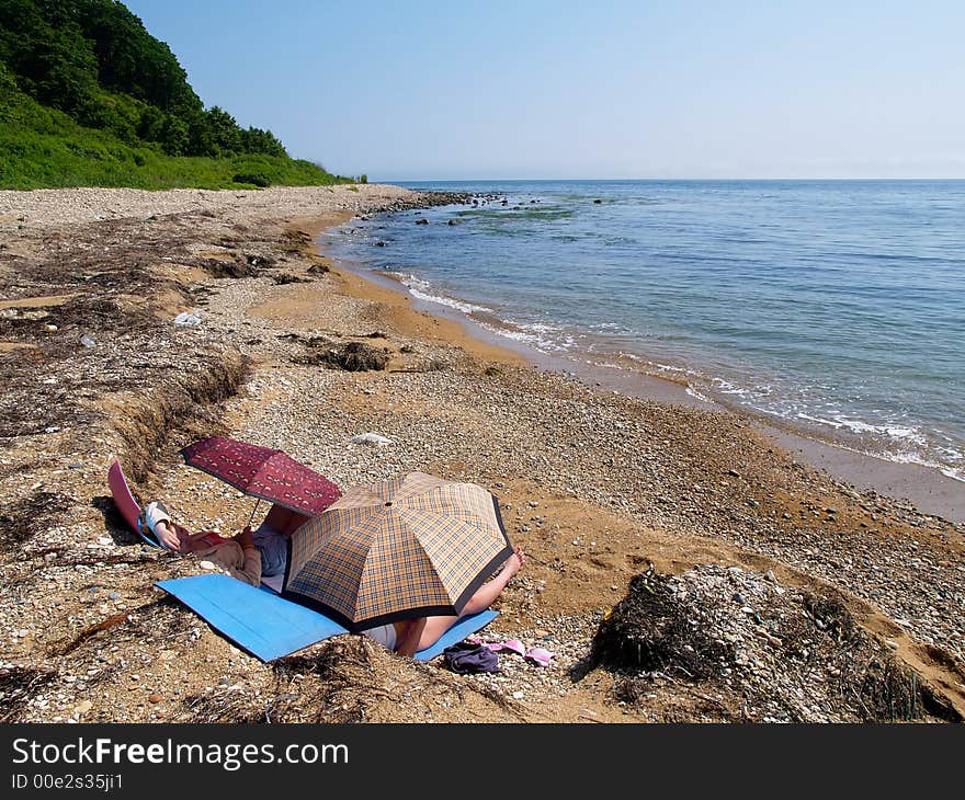 sea landscape with couple of girls resting on the wild ocean beach  . sea landscape with couple of girls resting on the wild ocean beach