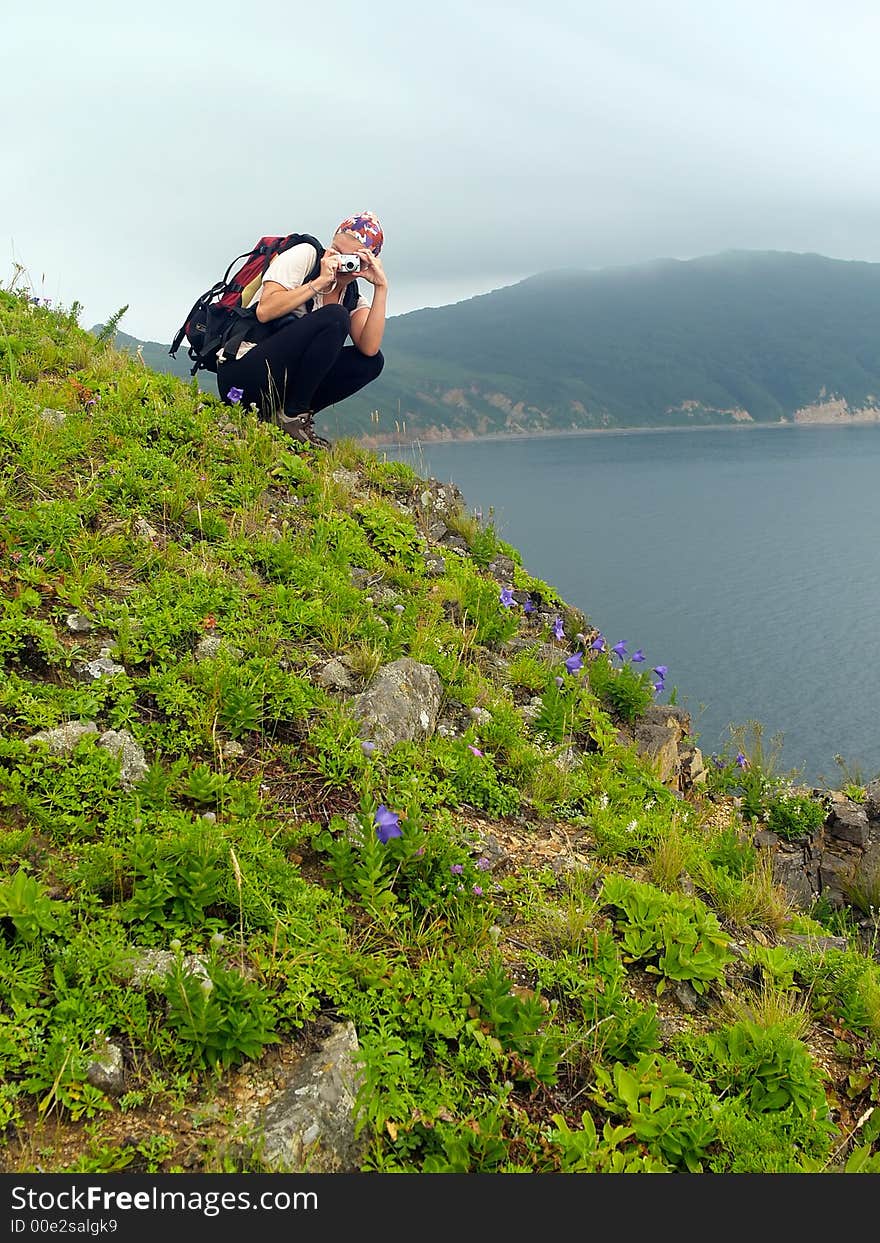 sea coastal landscape with young hiking woman shooting on the digital camera ont he ocean hill . sea coastal landscape with young hiking woman shooting on the digital camera ont he ocean hill