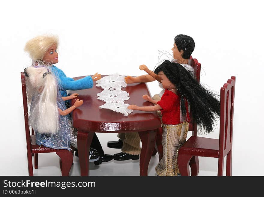 A macro shot of a toy family sitting at a dining table. isoalated on white. A macro shot of a toy family sitting at a dining table. isoalated on white