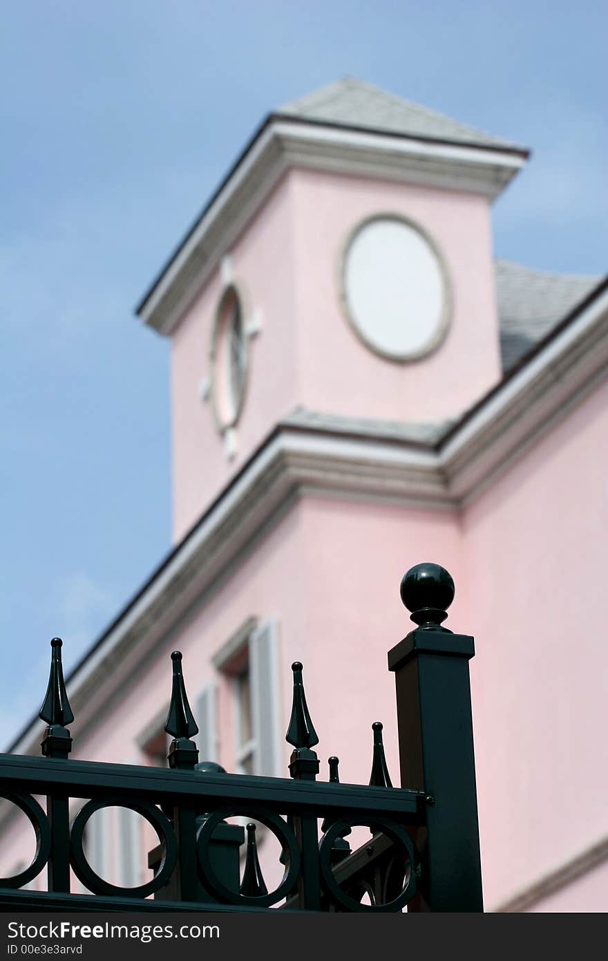 Black wrought iron fence with OOF pink building in background. Black wrought iron fence with OOF pink building in background