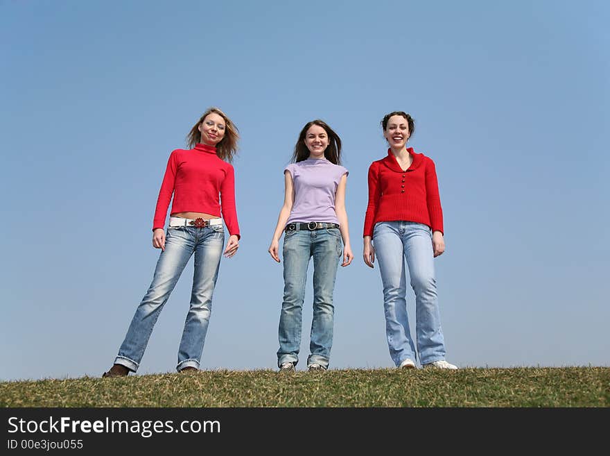 Girls stand on meadow against a blue sky