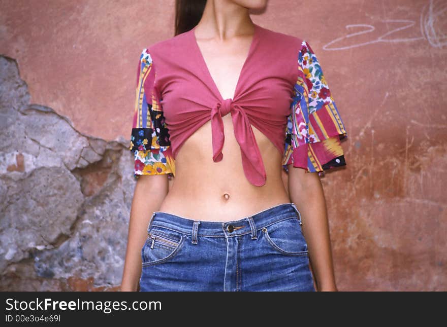 Girl in vest costs on background of old destroyed wall. Girl in vest costs on background of old destroyed wall