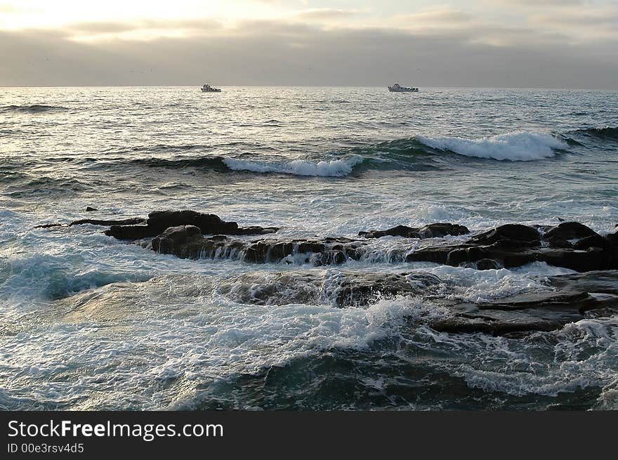 Sunset at theSan Diego ocean with boats and rock in the foreground. Sunset at theSan Diego ocean with boats and rock in the foreground