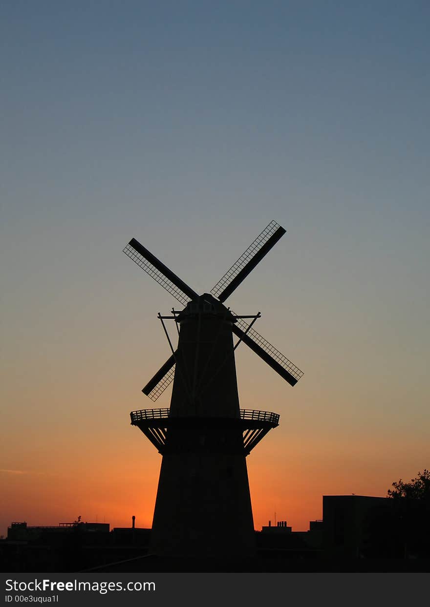 Windmill at the sunset. This is the tallest classic windmill in the world. The windmill is placed at the center of the picture. Windmill at the sunset. This is the tallest classic windmill in the world. The windmill is placed at the center of the picture.