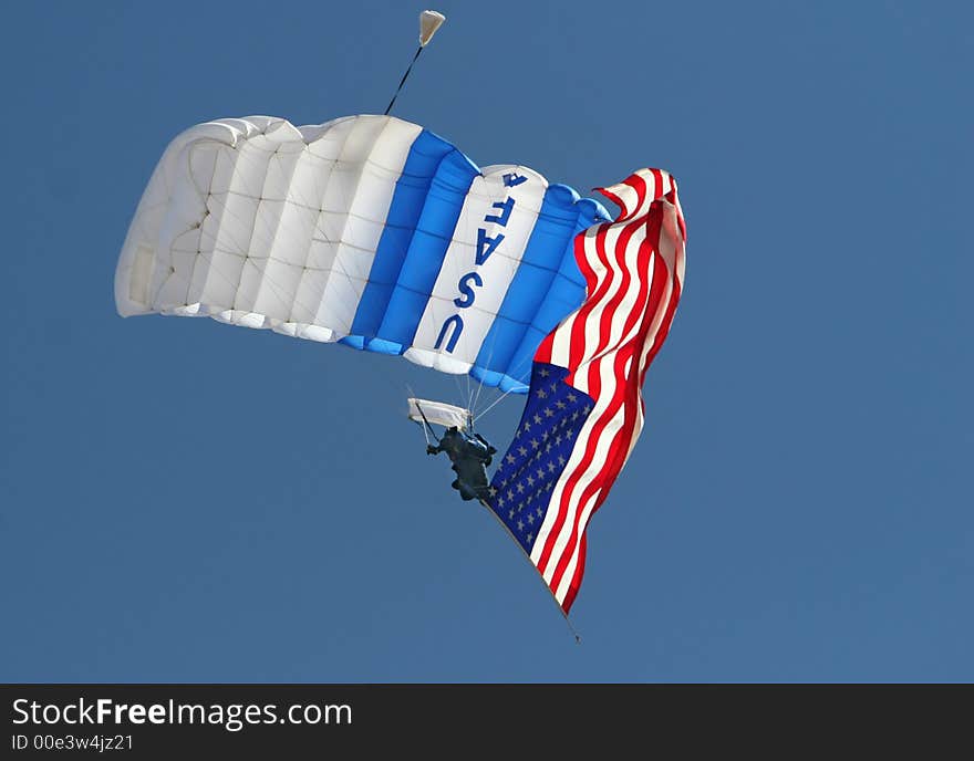 A USAF parachute jumper trails an american flag at an airshow