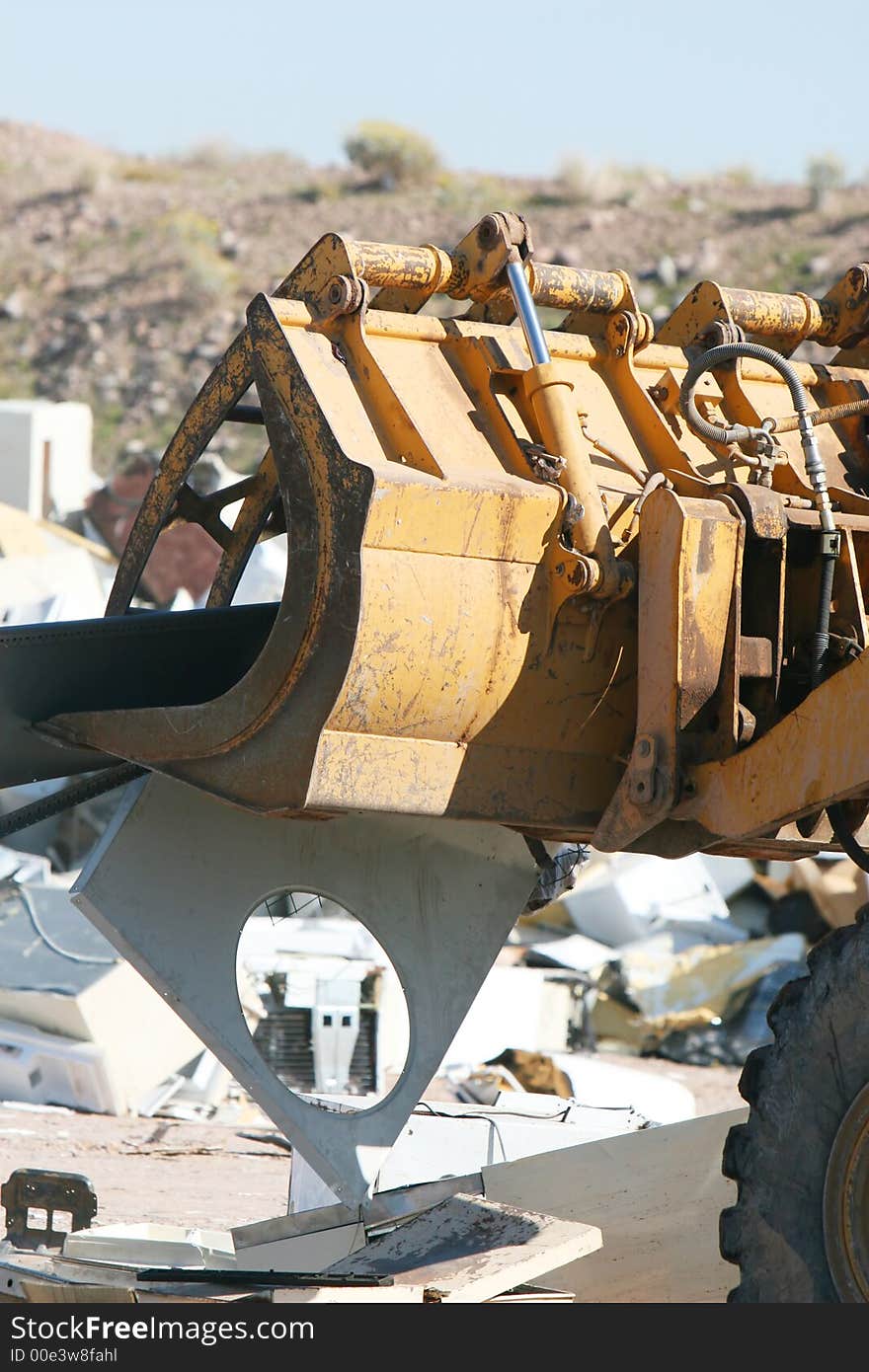 A bulldozer crushes and moves a giant stack of refrigerators, air conditioners, and stoves. A bulldozer crushes and moves a giant stack of refrigerators, air conditioners, and stoves.