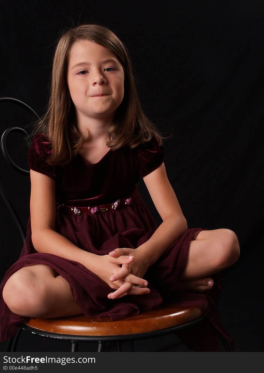 Brunette little girl sitting on a chair. Brunette little girl sitting on a chair