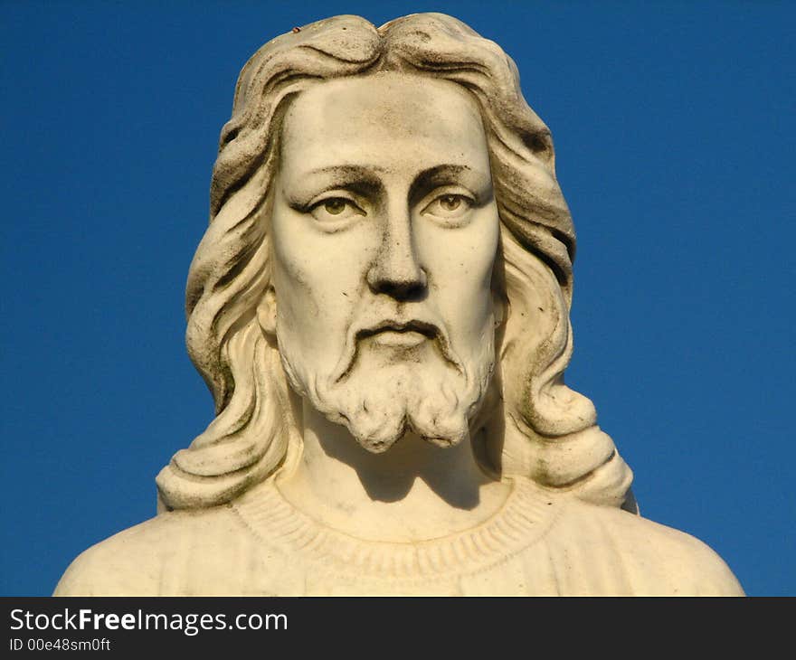 A statue of Jesus from the shoulders up with a blue sky in the background. A statue of Jesus from the shoulders up with a blue sky in the background.