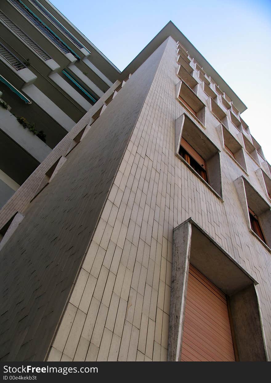 Tall building with angular windows towards blue sky. Tall building with angular windows towards blue sky