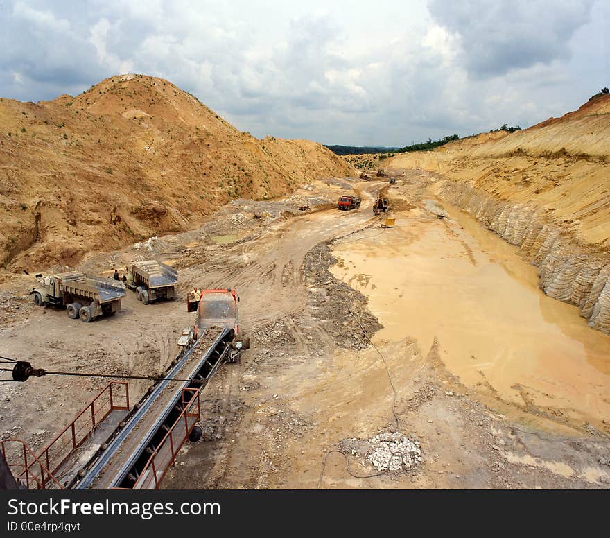 The Crushed stone, pouring elevated conveyor onto a dump truck against blue sky. The Crushed stone, pouring elevated conveyor onto a dump truck against blue sky