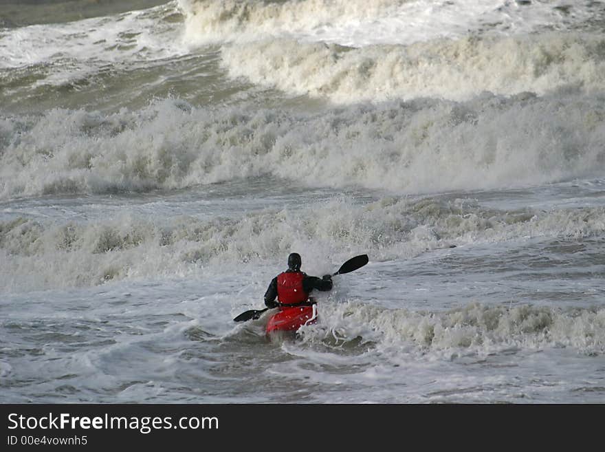 During flood a canoe is fighting against the waves. During flood a canoe is fighting against the waves.