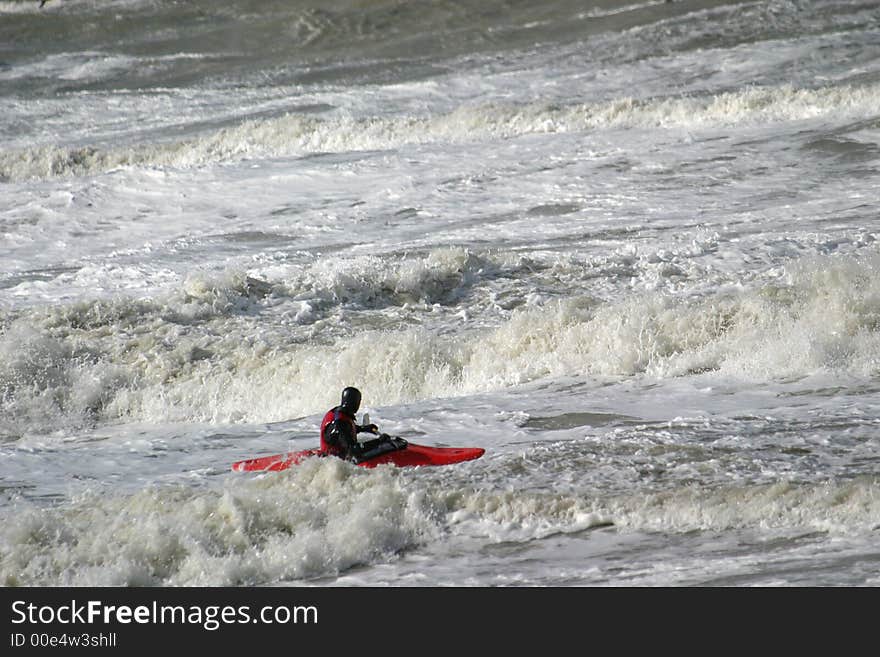 During flood a canoe is fighting against the waves. During flood a canoe is fighting against the waves.