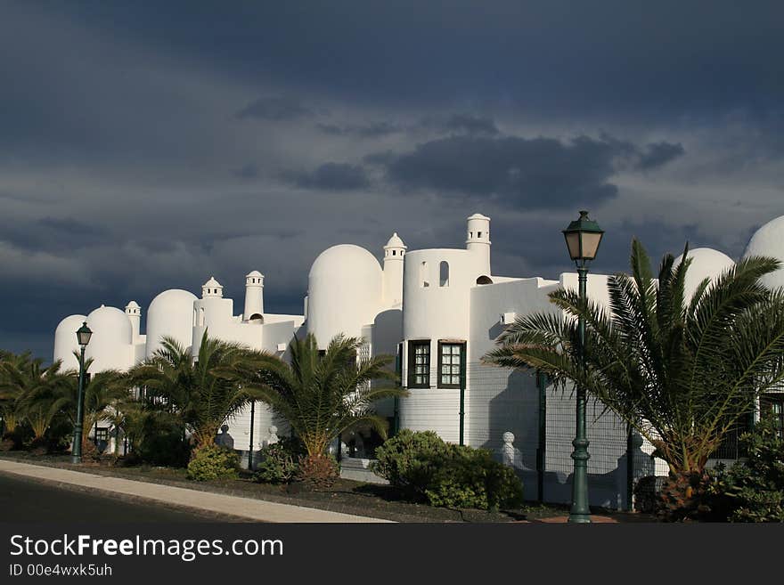 Grey darkening skies above white moorish holiday home storm palm