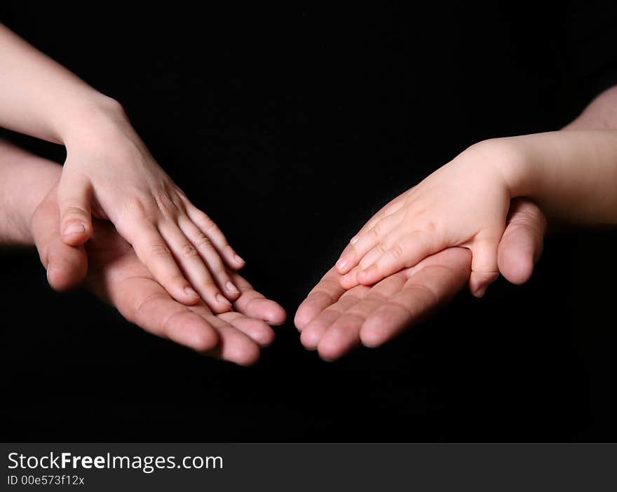 Hands of the father and his daughters on a dark background. Hands of the father and his daughters on a dark background