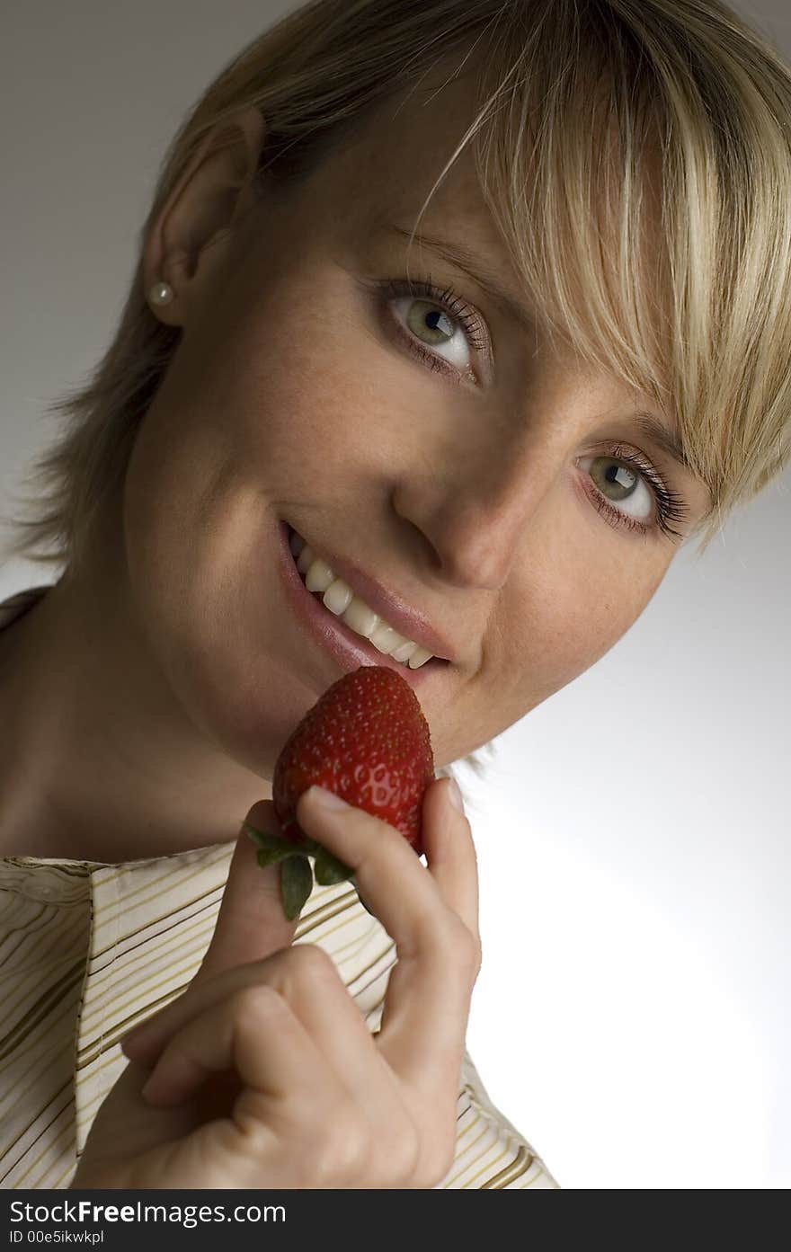 Young blond woman holding strawberry in her hand