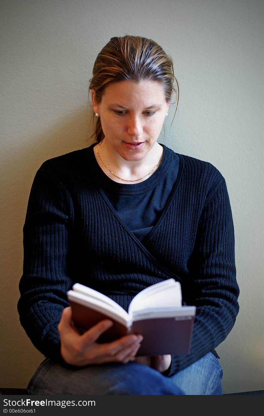 A young woman absorbed in her book with soft sideway lighting. A young woman absorbed in her book with soft sideway lighting