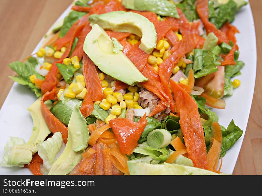 Salmon salad with sweet corn and vegetables on white dish