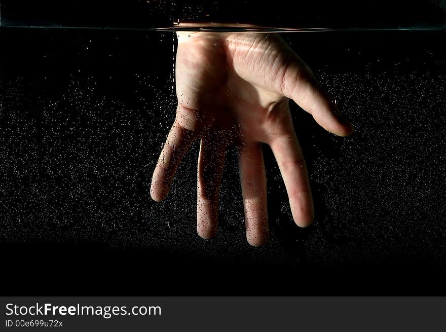 Photo of hand in the water on a black background.