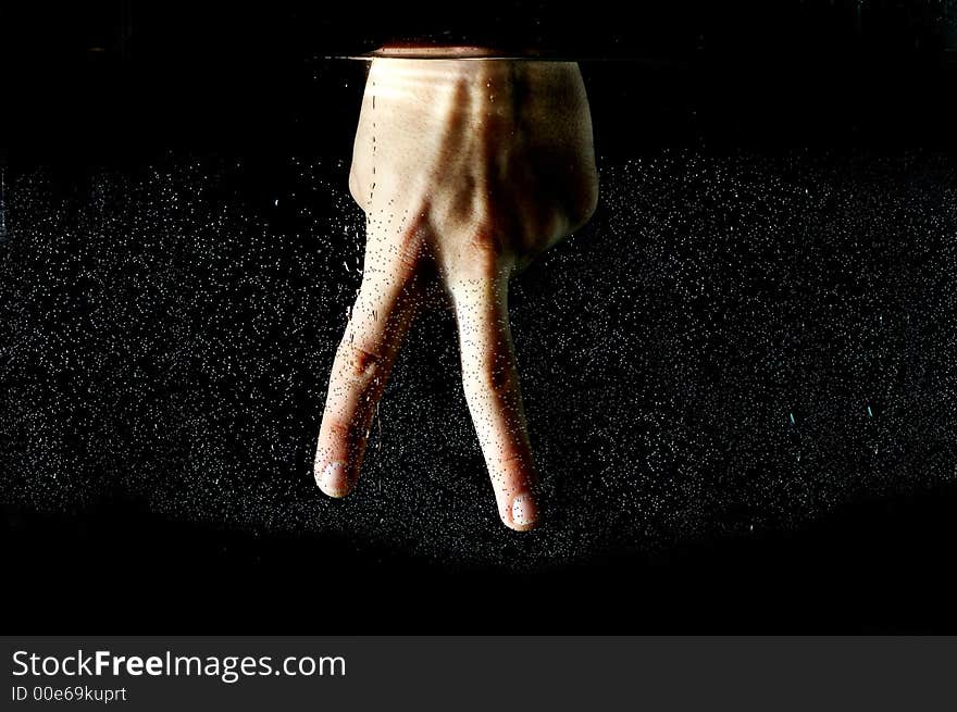 Photo of hand in the water on a black background.