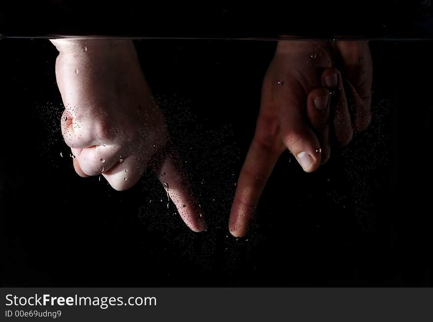 Photo of hand in the water on a black background.