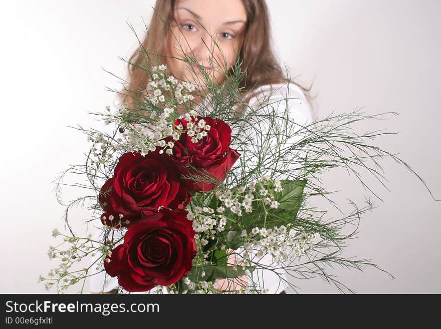 A young attractive brunette offering a bouquet of red roses. A young attractive brunette offering a bouquet of red roses