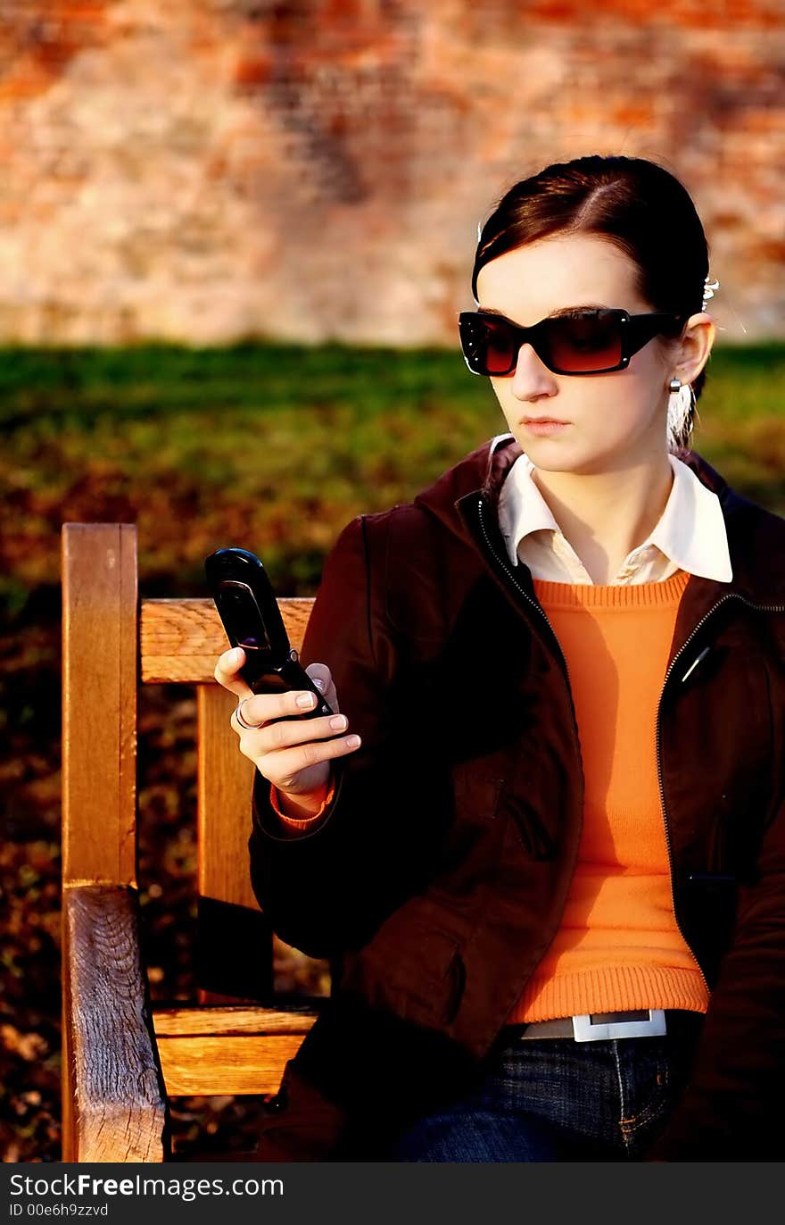 Photo of pretty female in sunshine light with cell phone. Photo of pretty female in sunshine light with cell phone.