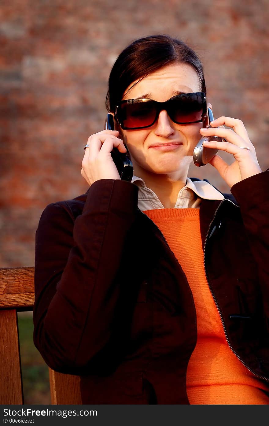 Photo of pretty female in sunshine light with two cell phones. Photo of pretty female in sunshine light with two cell phones.