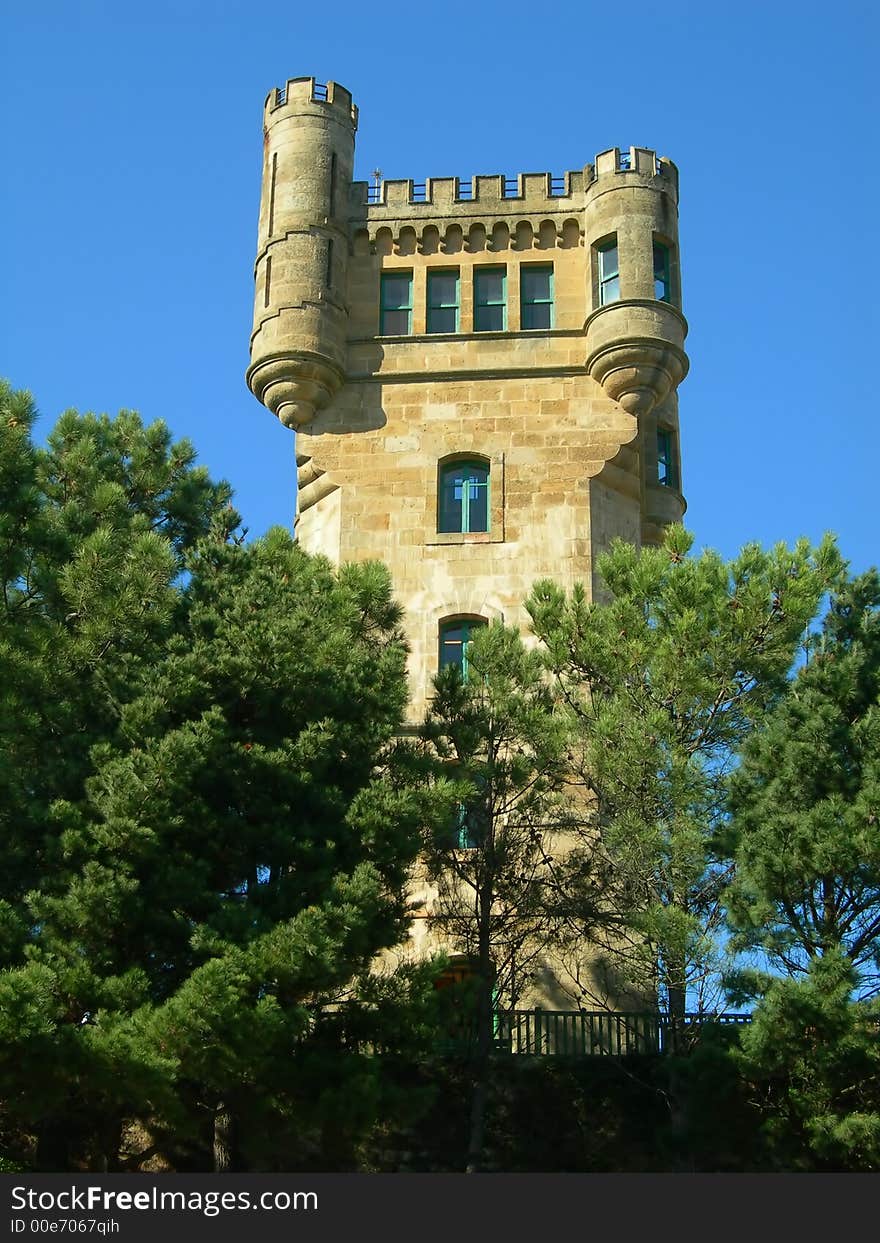 Ancient tower behind trees in a sunny day