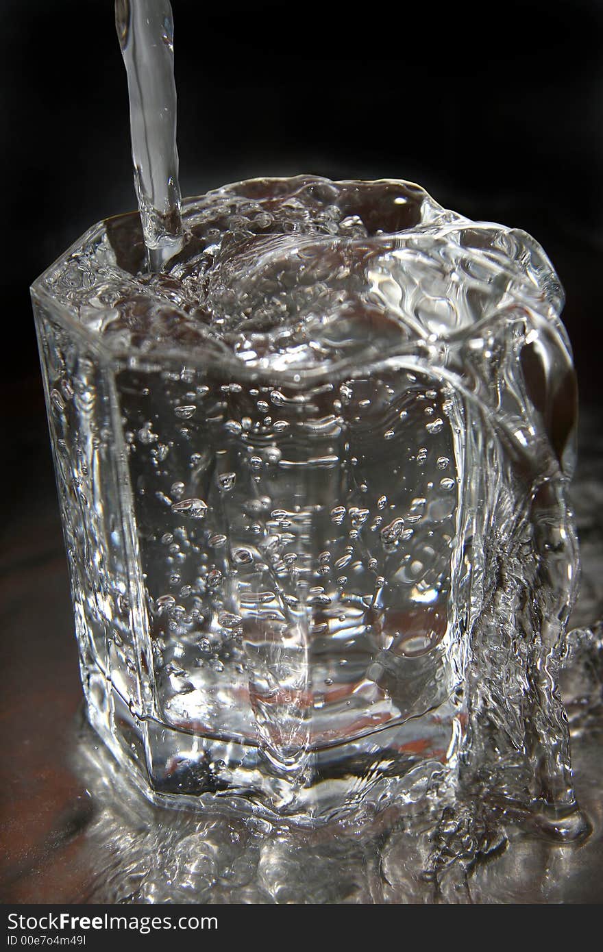 Jet of water flowing in the filled thick glass tumbler. Jet of water flowing in the filled thick glass tumbler.