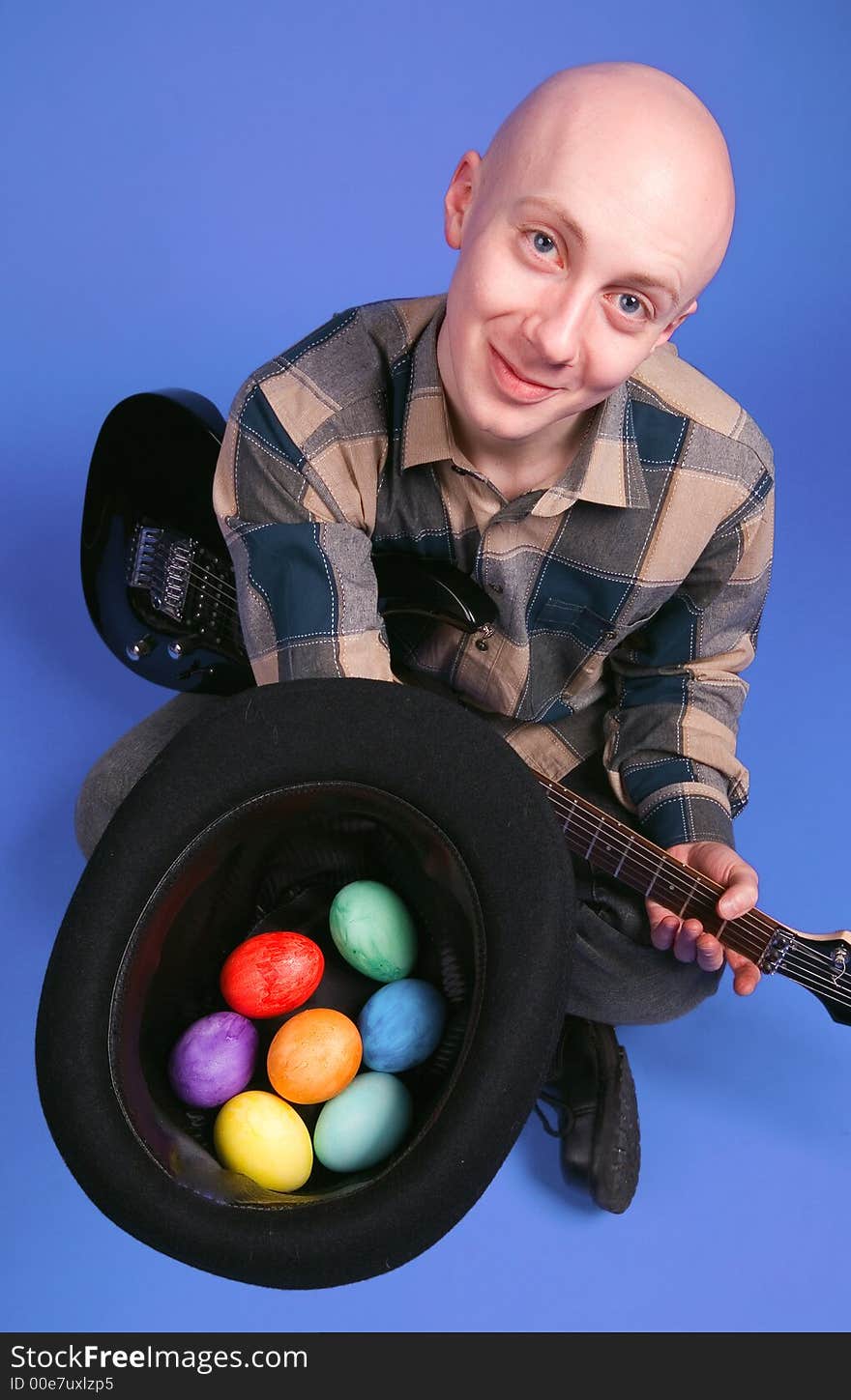 The musician with a guitar and easter eggs sits on a dark blue background. The musician with a guitar and easter eggs sits on a dark blue background