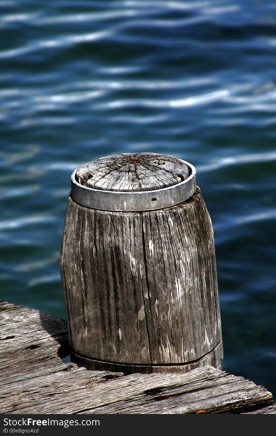 Wooden Pole Marking A Footpath Next To The Blue Ocean Surface