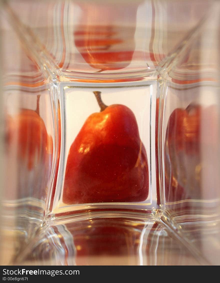 Red ripe pear in the glass box. Bright reflections.