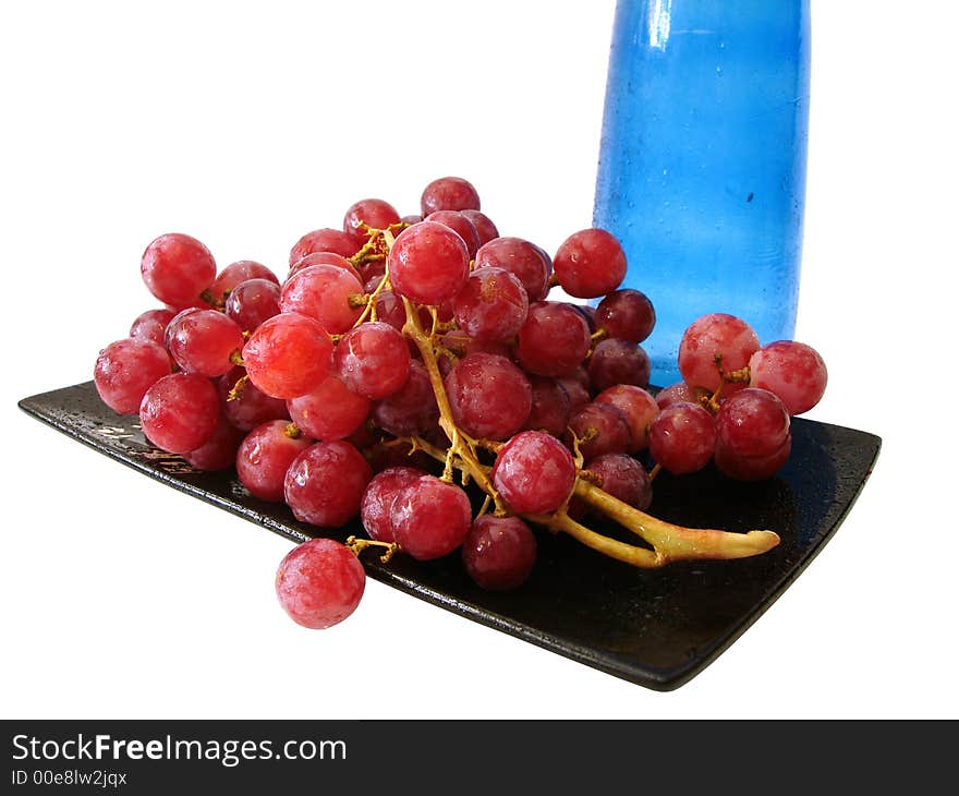 Dish with grapes and blue bottle over white background. Dish with grapes and blue bottle over white background